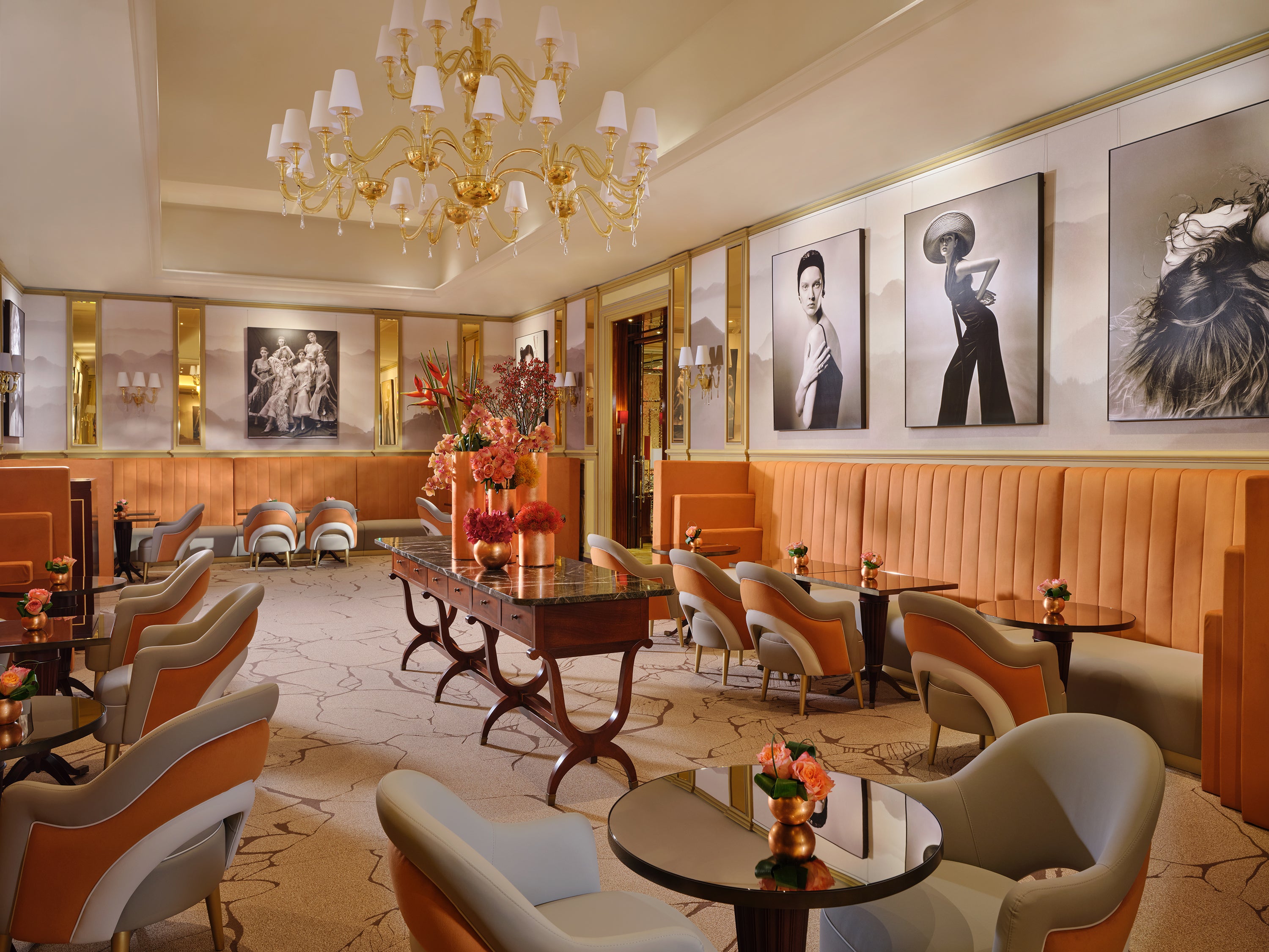 Sophisticated lounge featuring elegant furniture, floral arrangements, and black-and-white fashion portraits on the walls.