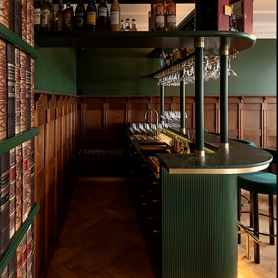 Stylish bar interior featuring wooden paneling, stacked liquor bottles, and a sleek countertop with glasses.
