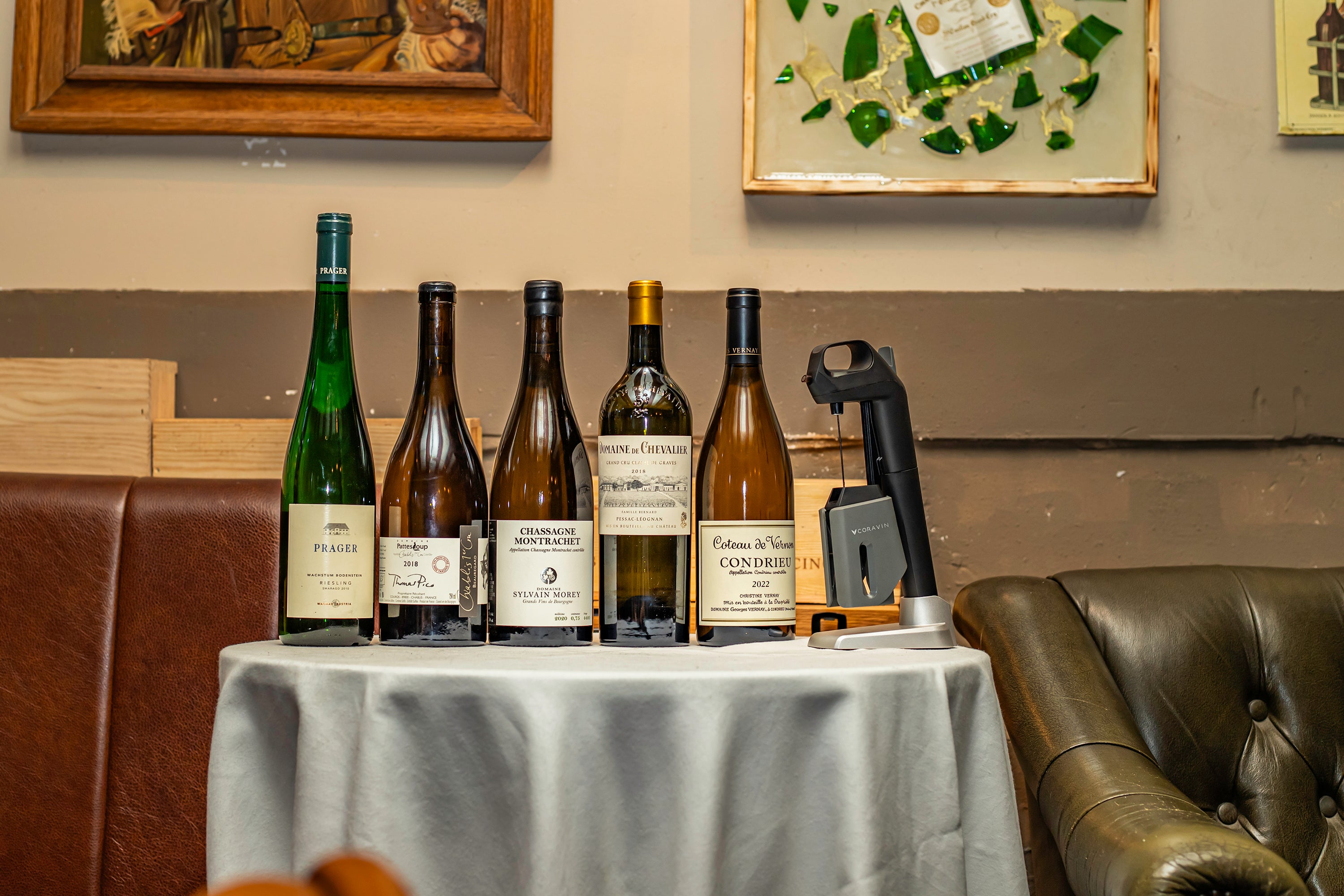 Various bottles of wine displayed on a table with a wine opener beside them, set in a cozy environment.