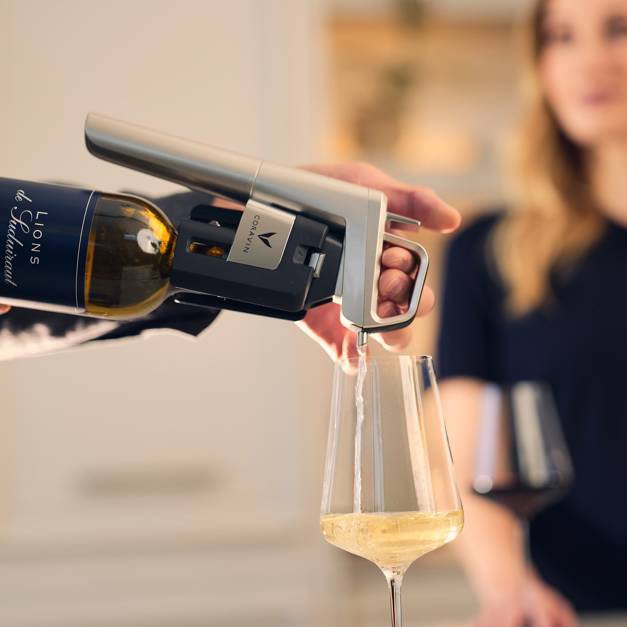 Person pouring wine from a bottle into a glass using a Coravin